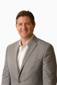 certified financial planner Marshall Clay wears a gray jacket and white shirt while posing for professional photo in office